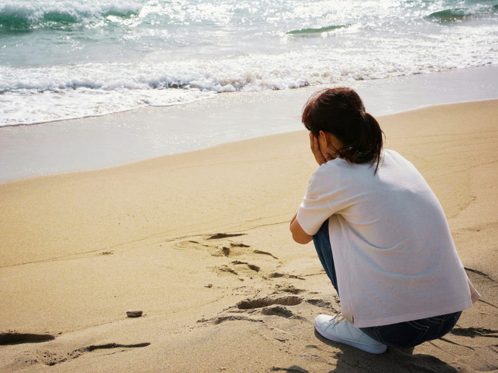海辺で悩む女性